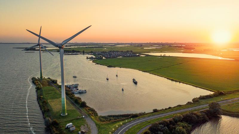 This is an aerial photo of wind turbines and the sun setting. They are located on the roead connecting the Dutch mainland to the former island of Marken. The sea surrounding the wind turbines is Markermeer.