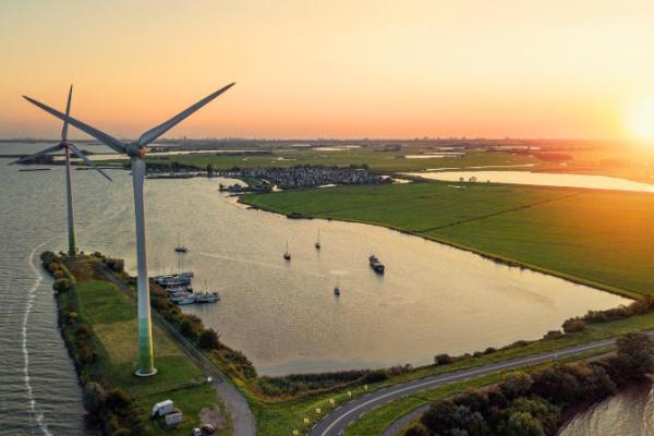 This is an aerial photo of wind turbines and the sun setting. They are located on the roead connecting the Dutch mainland to the former island of Marken. The sea surrounding the wind turbines is Markermeer.
